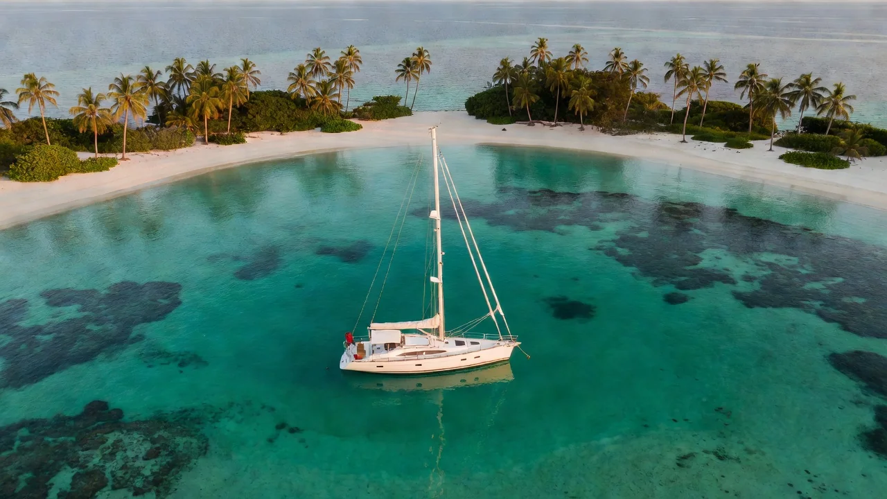Sailing yacht at anchor off a remote tropical atoll with a turquoise lagoon